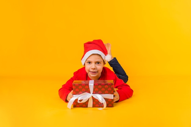 Mały chłopiec w czerwonej czapce na podłodze z prezentem