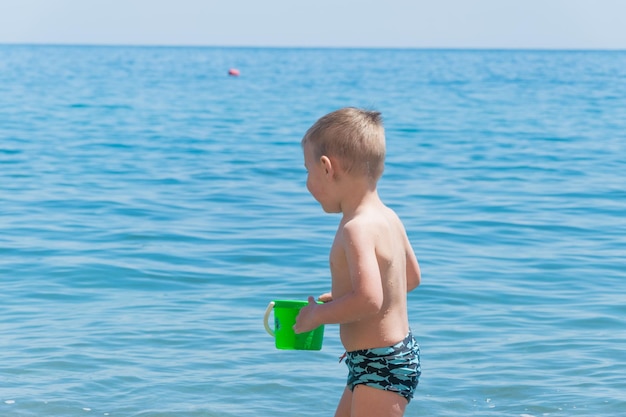 Mały chłopiec w kąpielówkach bawi się na plaży