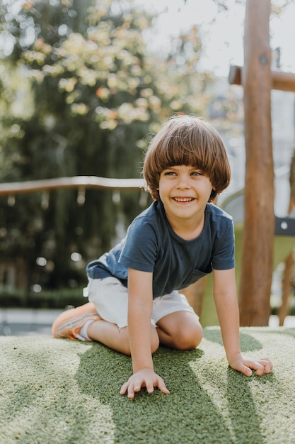 Mały chłopiec w niebieskiej koszulce i białych spodenkach siedzi na zielonej trawie na placu zabaw. dziecko aktywnie spędza czas bawiąc się i spacerując na świeżym powietrzu. styl życia. miejsce na tekst. Zdjęcie wysokiej jakości