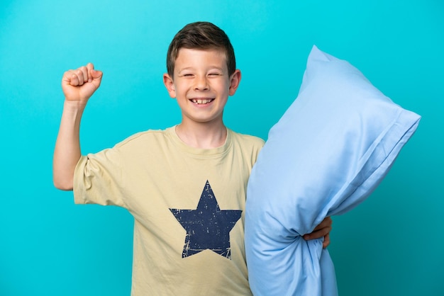 Mały chłopiec w piżamie na niebieskim tle robi mocny gest