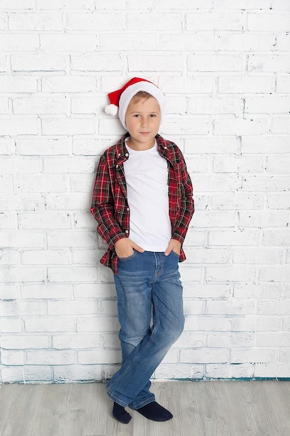 Mały chłopiec w santa hat z piernika na białym tle Szczęśliwego nowego roku kartka Czekam na święta