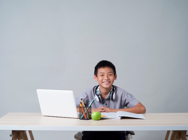 Mały Chłopiec W Słuchawkach Studiuje Online Za Pomocą Laptopa