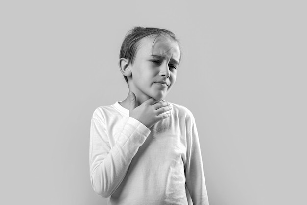 Zdjęcie mały chłopiec z bólem gardła dotyka jej szyi mały mężczyzna ma ból w gardle