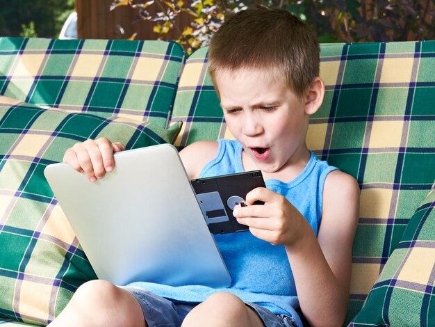 Mały chłopiec z dyskietką i komputerem typu tablet