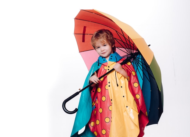 Mały chłopiec z parasolem w kolorze tęczy na białym tle. Wyprzedaż całej jesiennej kolekcji, niesamowite rabaty i wspaniały wybór. Ładny mały chłopiec dziecko szykuje się na jesień.