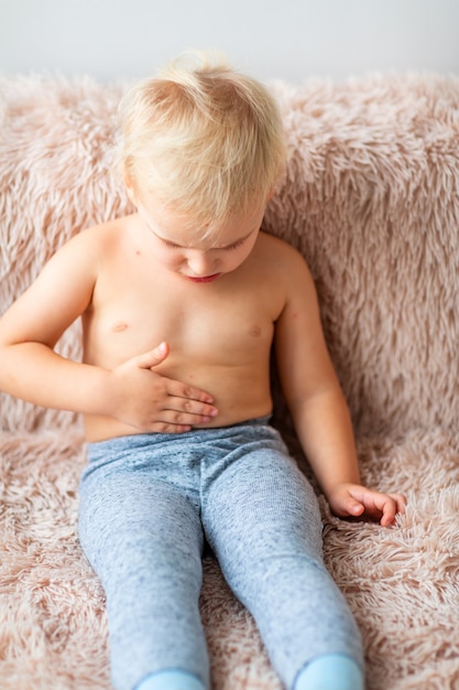 Zdjęcie mały chłopiec z wirusem ospy wietrznej lub wysypką pęcherzykową ospy wietrznej drapie się po ciele w domu