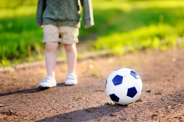 Mały Chłopiec Zabawy Grając W Piłkę Nożną / Mecz Piłki Nożnej W Letni Dzień