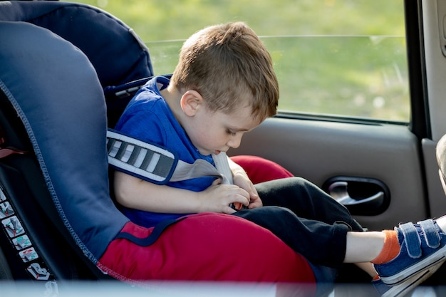 Mały chłopiec zapiął pasy w samochodzie. Koncepcja pojazdu i transportu.