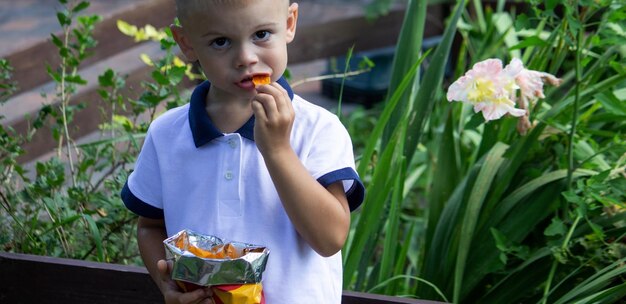 Mały chłopiec zjada chipsy ziemniaczane z paczki