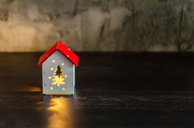 Mały dom z oknami w kształcie choinki, które świecą w ciemnych lampkach świątecznych