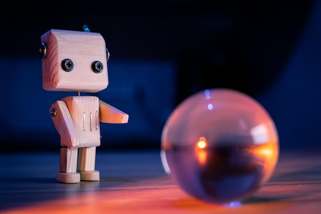 Mały drewniany zabawkowy robot patrzy na magiczną szklaną kulkę na ciemnym, niebieskim tle