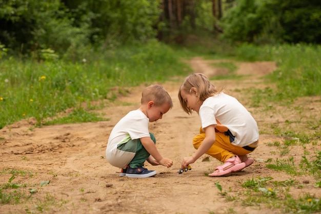 Mały kaukaski chłopiec i dziewczynka bawią się latem na świeżym powietrzu w lesie