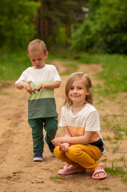 Mały kaukaski chłopiec i dziewczynka bawią się latem na świeżym powietrzu w lesie