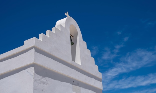 Mały kościelny dzwonnica szczegół kaplica białego koloru na jasnym niebieskim tle Grecja