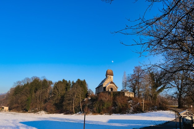 Zdjęcie mały kościół stoi na śnieżnym polu z niebieskim niebem na tle