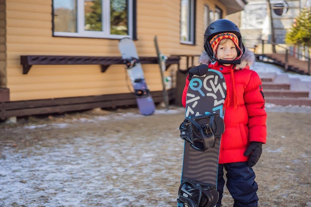 Mały ładny chłopiec jest gotowy do zajęć na snowboardzie dla dzieci w sporcie zimowym dla dzieci