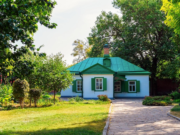 Mały parterowy biały dom z rustykalną architekturą z zielonym dachem