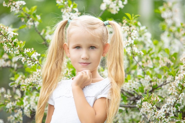 Zdjęcie mały piękny portret dziewczynki na tle kwitnącego drzewa na wiosnę