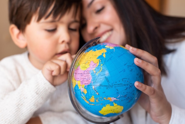 Mały przedszkolak uczy się geografii z mapą globu i pomocą nauczyciela. Pomoc domowa. Społeczność edukacyjna. Szkoła Montessori