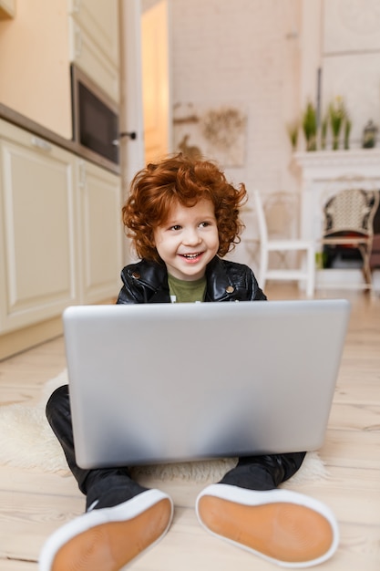 Zdjęcie mały rudy chłopiec używa laptopa