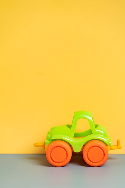 Mały samochód zabawka dla dzieci na żółtym tle. Tło dla dzieci.