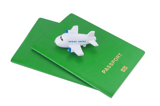 Mały samolot zabawkowy na zielonych paszportach na białym tle