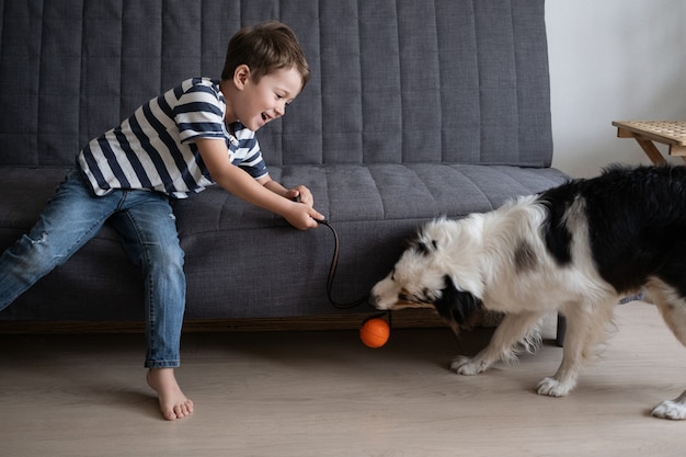 Zdjęcie mały szczęśliwy chłopiec bawi się piłką z owczarkiem australijskim