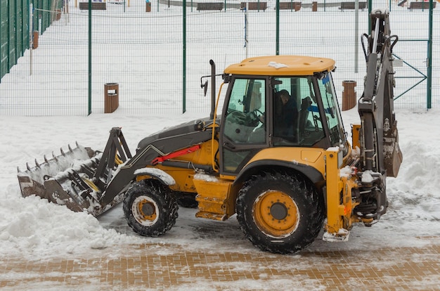 Mały traktor odśnieża drogę w pobliżu domu