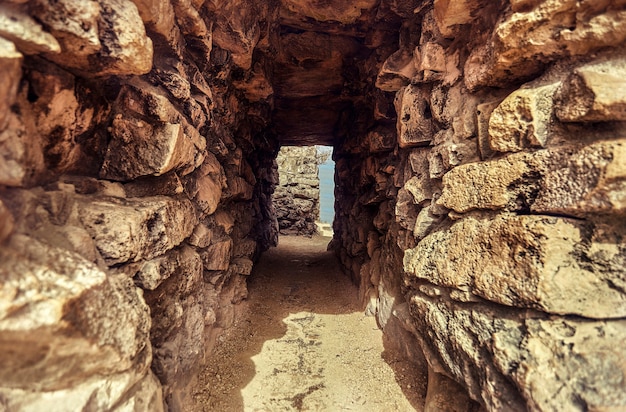 Mały tunel z kamiennymi ceglanymi ścianami tworzy przejścia między murami ruin Tulum w Meksyku
