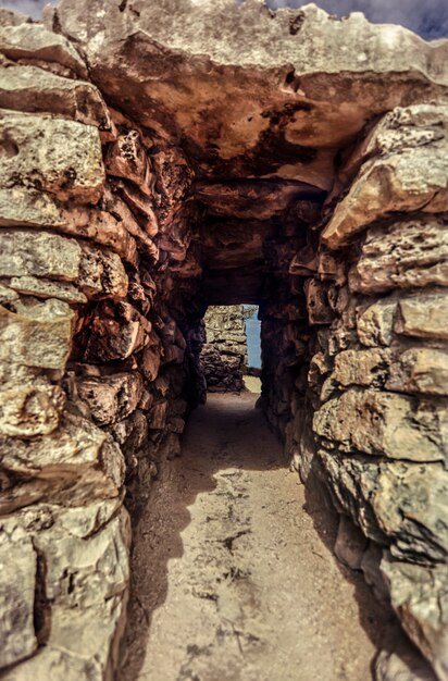 Mały tunel z kamiennymi ceglanymi ścianami tworzy przejścia między murami ruin Tulum w Meksyku