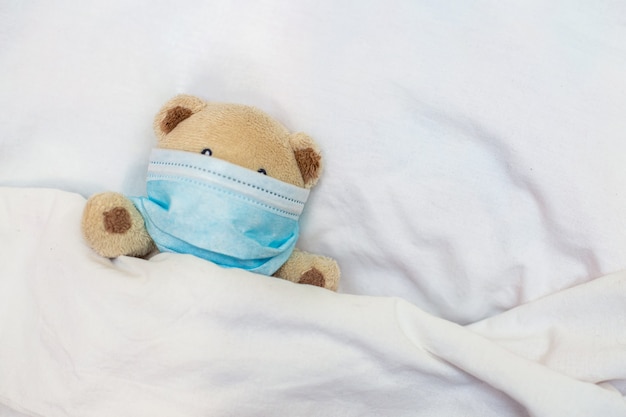 Mały zabawkowy miś leży w łóżku. Koronowirus, kwarantanna, epidemia, pandemia, grypa, przeziębienie, choroba. Pojęcie medycyny i zdrowie.