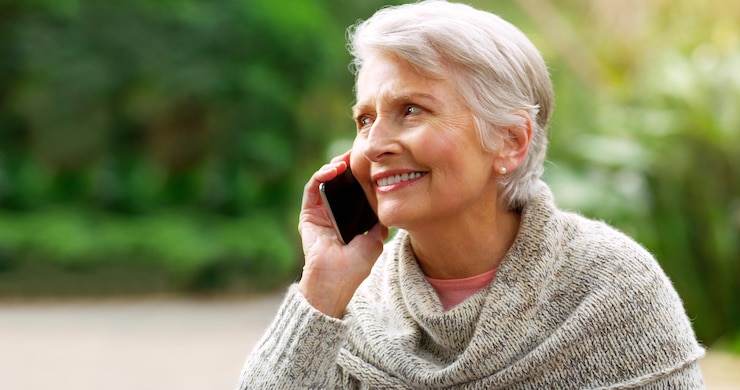 Zdjęcie mam to do pracy przycięte zdjęcie wesołej starszej kobiety rozmawiającej przez telefon na zewnątrz w parku