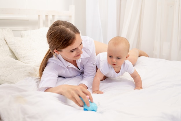 Mama Bawi Się Z Dzieckiem 6 Miesięcy Leżąc Na Białym łóżku, Wypoczynek Mama Z Dzieckiem, Miejsce Na Tekst