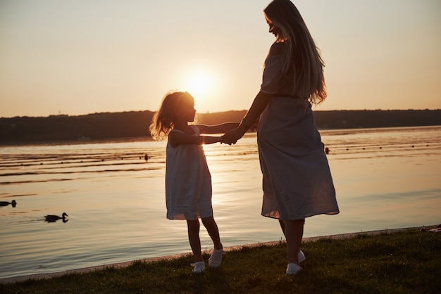 Mama Bawi Się Z Dzieckiem Na Wakacjach W Pobliżu Oceanu, Sylwetki O Zachodzie Słońca