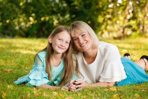 Mama blondynka z córką w parku latem przy słonecznej pogodzie