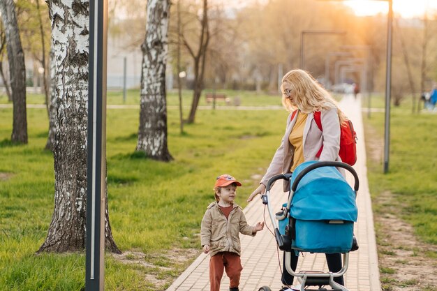 Zdjęcie mama chodzi z wózkiem i małym synem w parku.