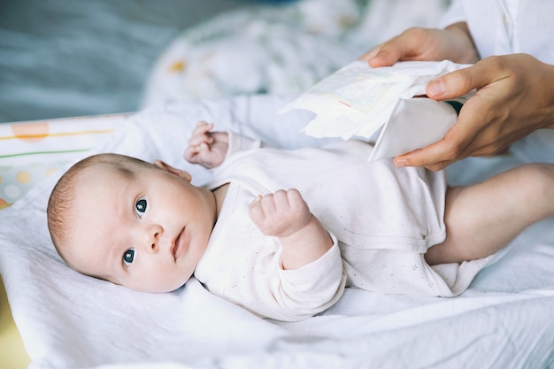 Mama delikatnie opiekuje się dzieckiem na przewijaku w domu Matka i uśmiechnięte najsłodsze noworodki