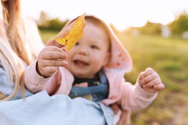 Mama dziecko bawi się w parku dziecko trzyma jesienne liście