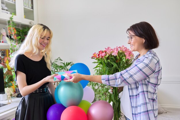 Mama gratuluje swojej nastoletniej córce prezentowymi kwiatami w domu w pokoju