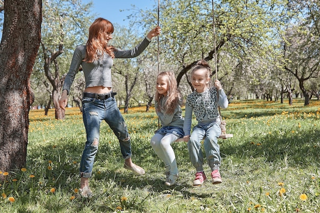 Zdjęcie mama huśta dzieci na huśtawce ogrodowej