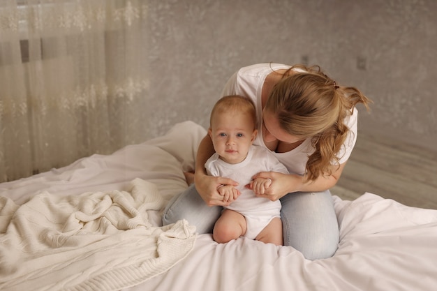 mama i córeczka przytulają się na białym prześcieradle macierzyństwo