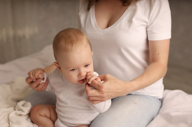 mama i córeczka przytulają się na białym prześcieradle macierzyństwo