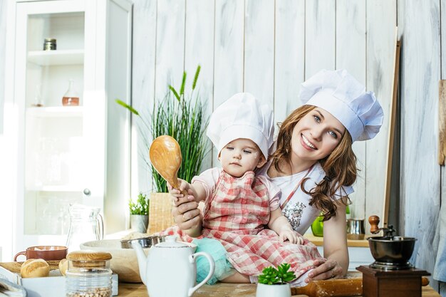 Mama i córeczka szczęśliwe i piękne przygotowują ciasto i mąkę w kuchni w domu