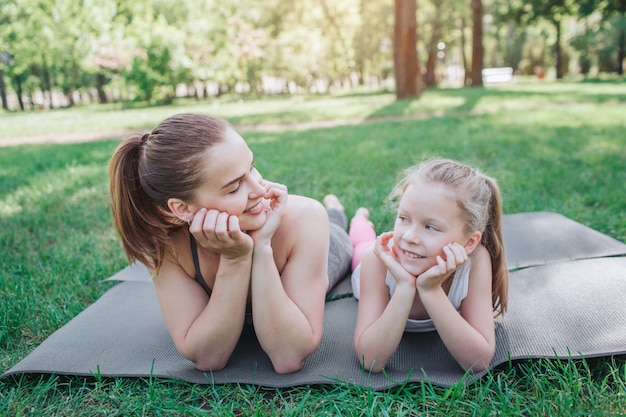 Mama i córka leżą na macie i patrzą na siebie