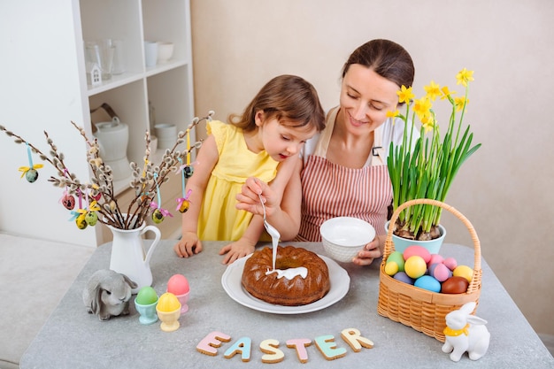 Mama i córka przygotowują ciasto wielkanocne i przykrywają je lukrem