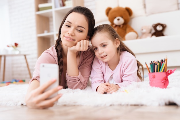 Zdjęcie mama i córka robią selfie na smartfonie.