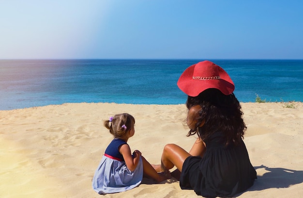 Mama i córka siedzą na plaży i patrzą na morze