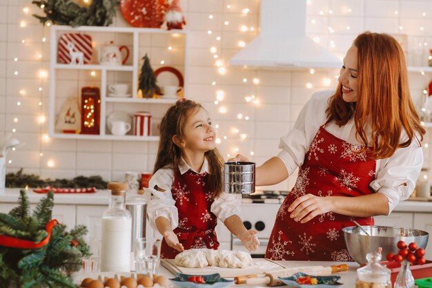 Mama i córka w noworocznej kuchni wspólnie przygotowują ciasto na świąteczne ciasteczka