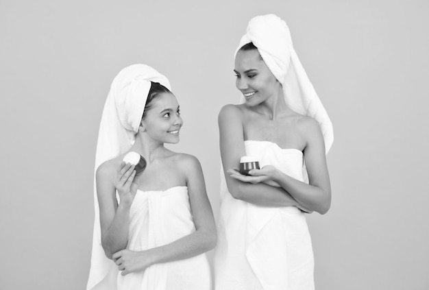 Mama i córka w ręczniku frotte dzień urody w spa rodzinnym spa matka i dziewczyna trzymają krem do twarzy