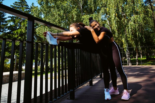 mama i córka w strojach sportowych w słoneczny letni dzień na nabrzeżu w parku uprawiają fitness